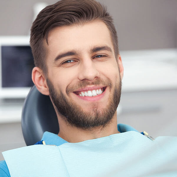 A man with a confident smile sits calmly in the dentist's chair, prepared for his oral surgery procedure.