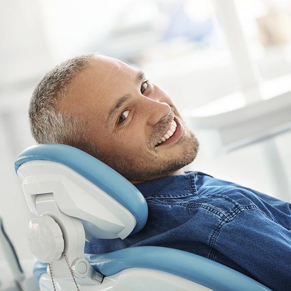 A mature man in the dentist's office waiting for his %title& while smiling
