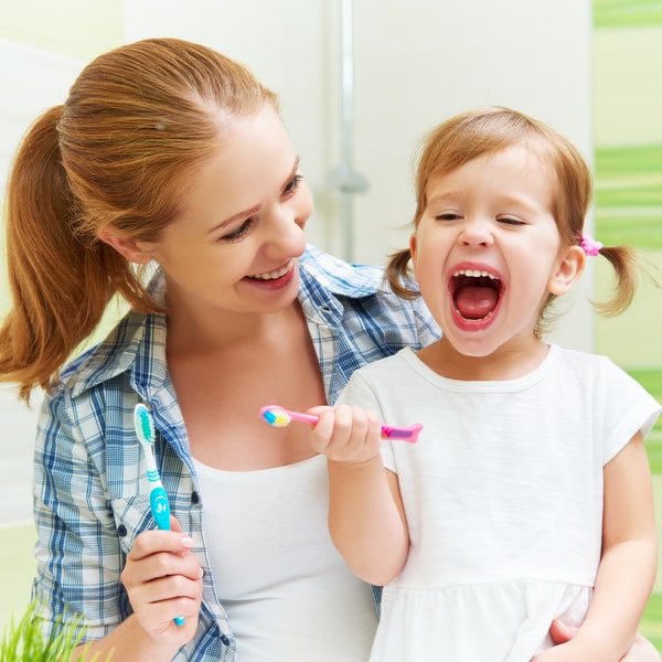 A young mother teaches her child how to brush teeth