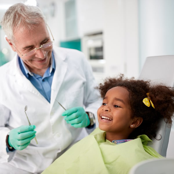 A young girl is smiling in a dental chair